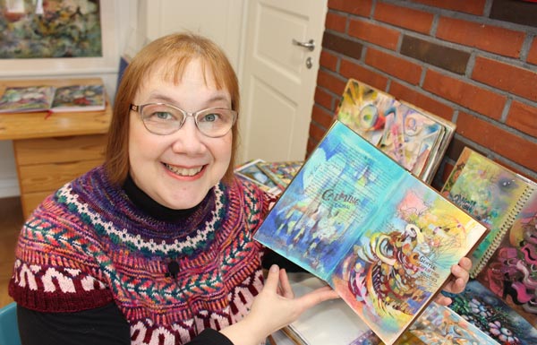Paivi Eerola with her journals, holding a music-inspired art journal.