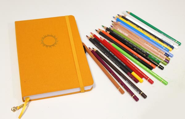 Archer & Olive notebook and a mixed selection of colored pencils.