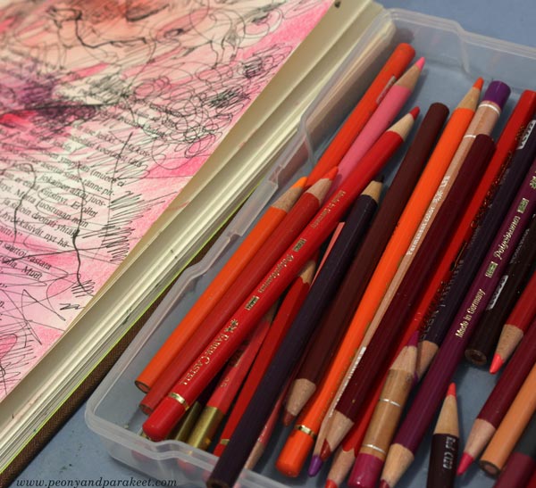 A box of red colored pencils and how to use them in an art journal.