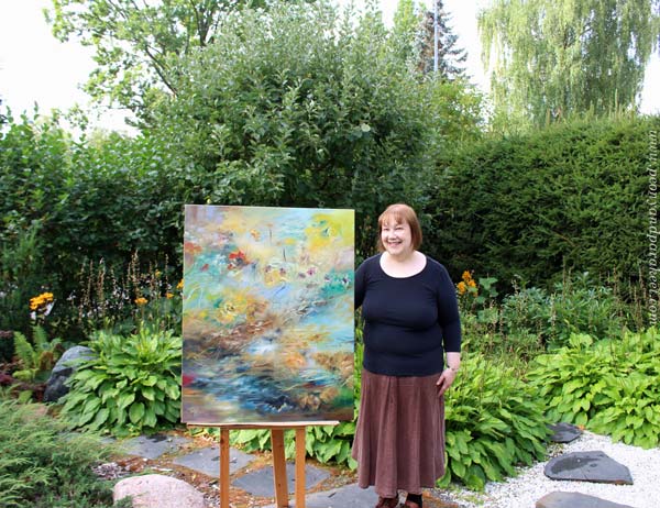Paivi Eerola and one of her paintings in a garden.
