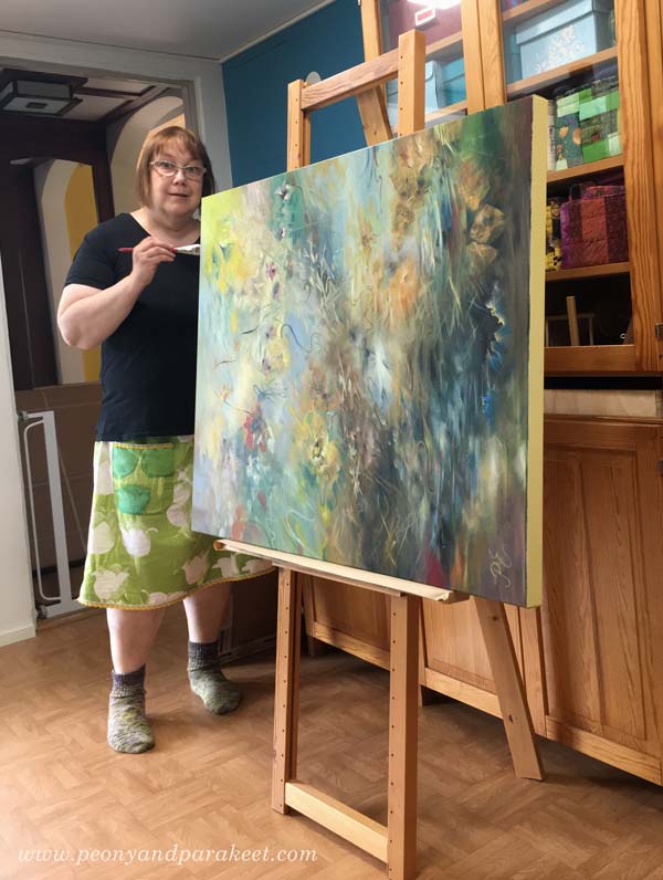 Painting the edges of a big painting. The painting is sideways on an easel.