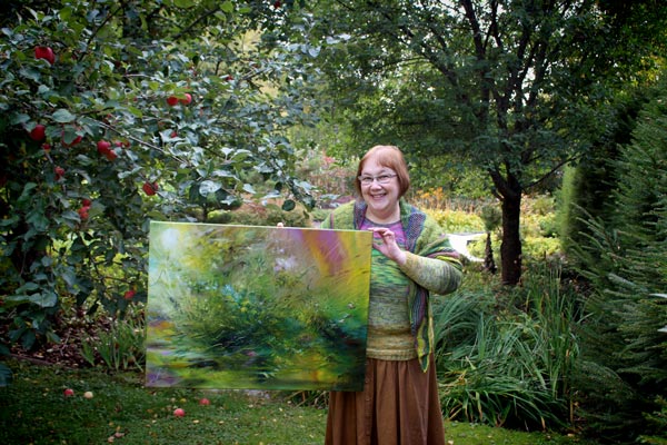 Paivi Eerola and her painting The Echo of Moss in the garden.