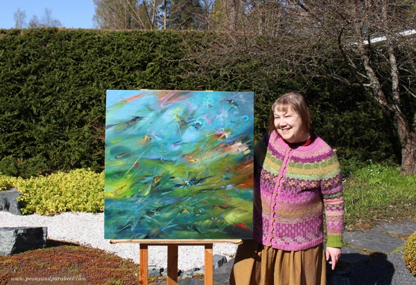 Painter of abstract birds. Paivi Eerola and her painting Kingfishers photographed in the garden.