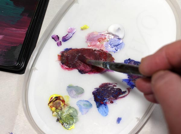 Mixing acrylic paints on a palette. You can use old lids as a palette.