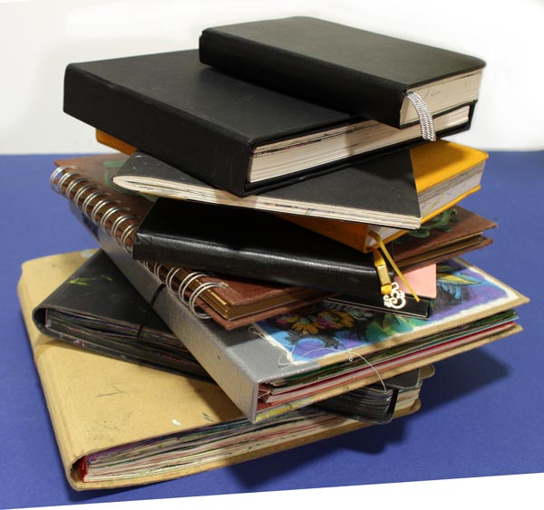Pile of art journals and sketchbooks., all half-empty. Reviewing art journals.