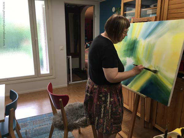 Artist painting in her studio while listening to music.