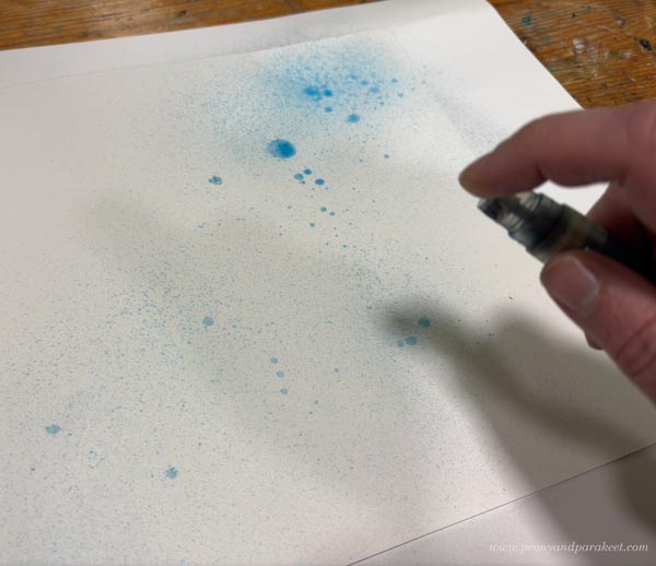 Starting a new drawing by spraying ink on paper.